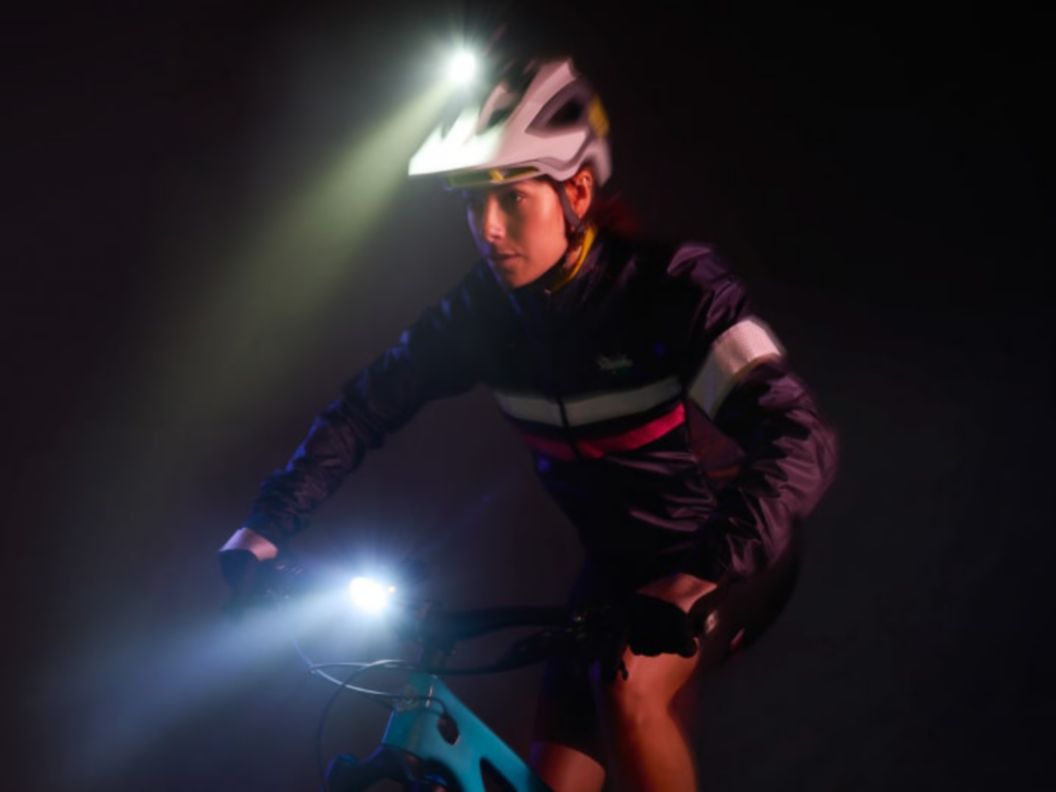 A rider in the dark wearing reflective riding apparel while using a helmet and a handlebar mounted front light.